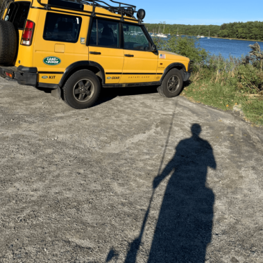 A shadow of Dan with a fishing pole headed toward his car